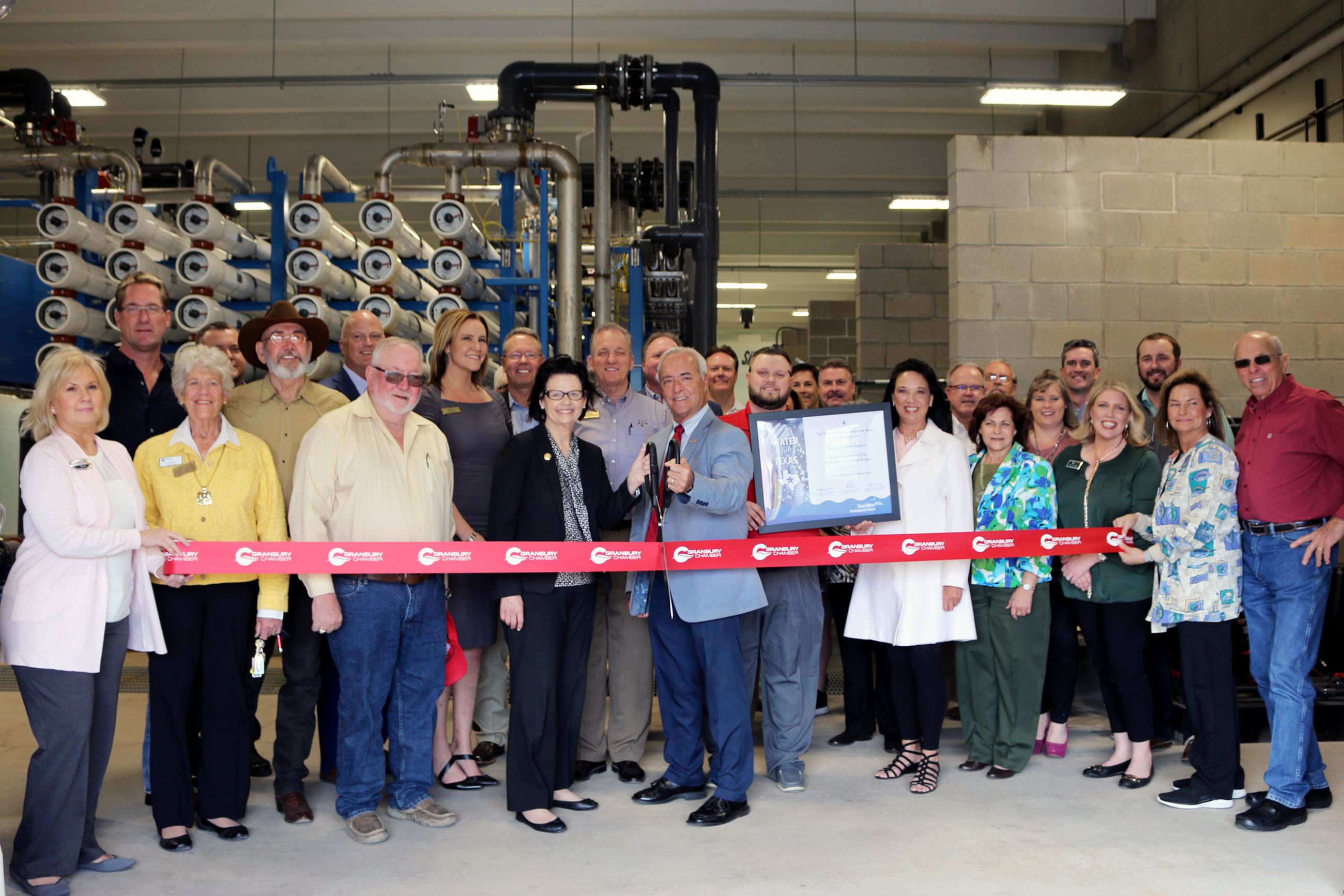 Group of attendees cutting ribbon at water treatment plant.