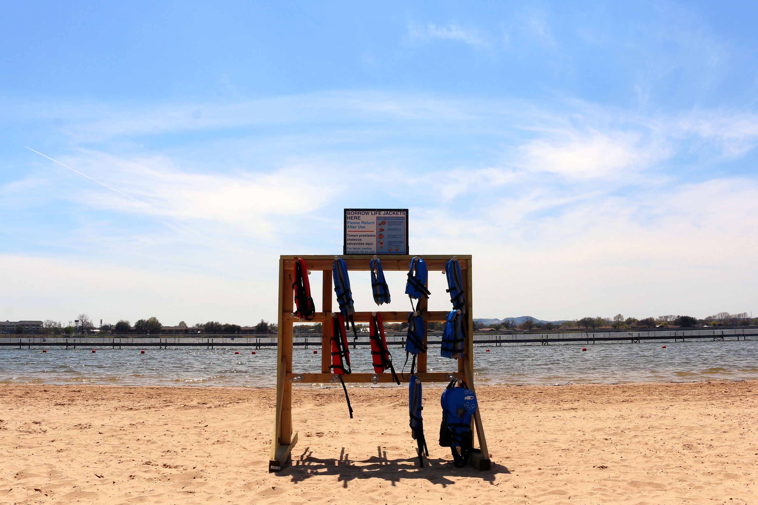 Wooden stand with lifejackets hanging on it on a beach.